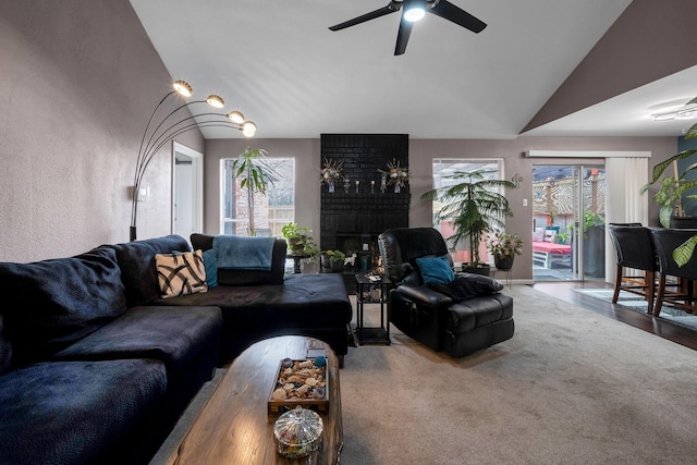 living area featuring a wealth of natural light, lofted ceiling, a fireplace, and a ceiling fan