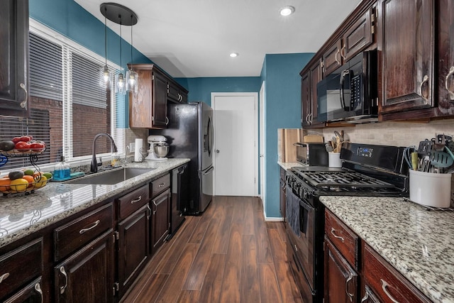 kitchen with dark wood-style floors, hanging light fixtures, decorative backsplash, a sink, and black appliances