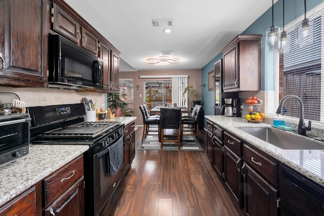 kitchen with black appliances, a sink, decorative light fixtures, and dark brown cabinetry