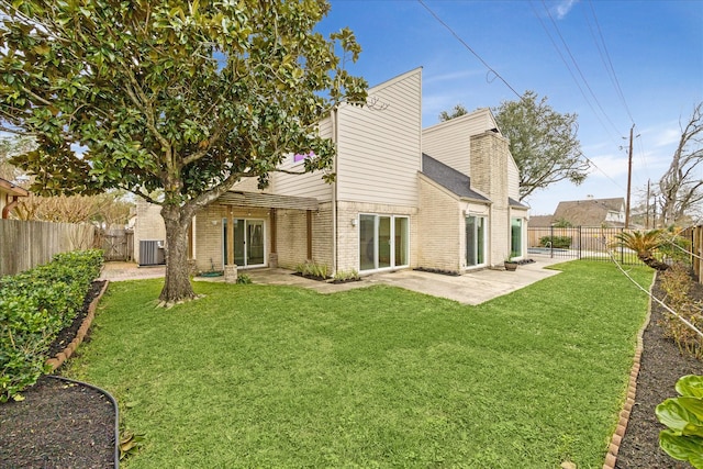 back of house with a patio area, a fenced backyard, a yard, and brick siding