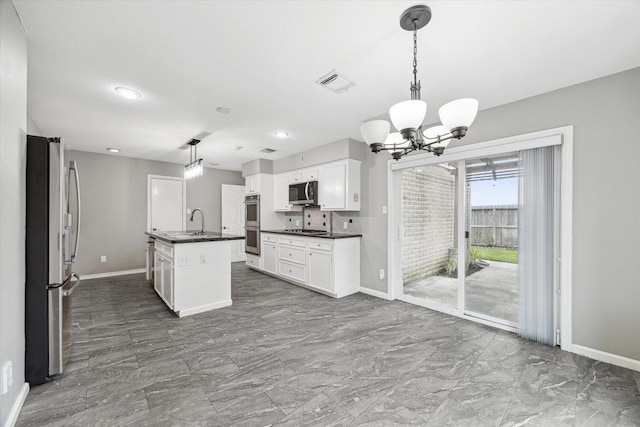 kitchen with dark countertops, white cabinetry, stainless steel appliances, and decorative light fixtures