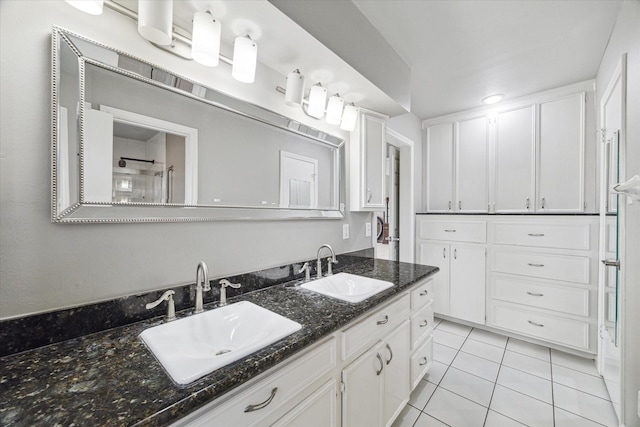 bathroom with a tile shower, double vanity, tile patterned flooring, and a sink