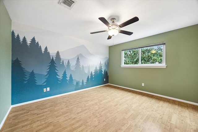 spare room featuring visible vents, ceiling fan, baseboards, and wood finished floors