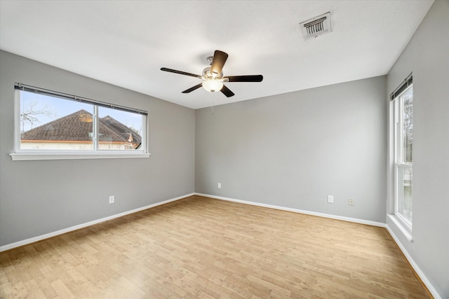 unfurnished room featuring a ceiling fan, baseboards, visible vents, and light wood finished floors