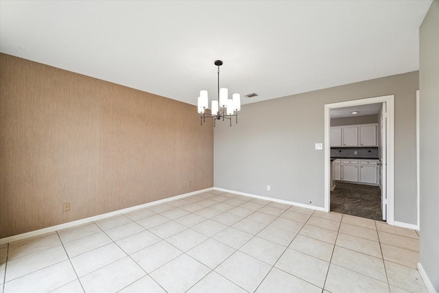 spare room featuring light tile patterned floors, baseboards, visible vents, and a chandelier