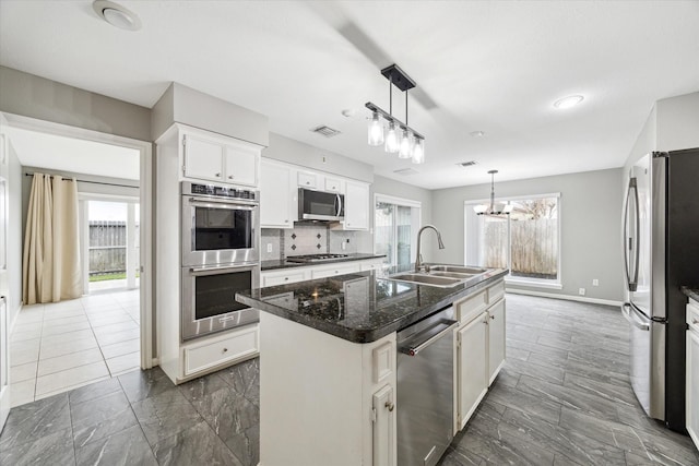 kitchen featuring visible vents, hanging light fixtures, appliances with stainless steel finishes, white cabinets, and an island with sink