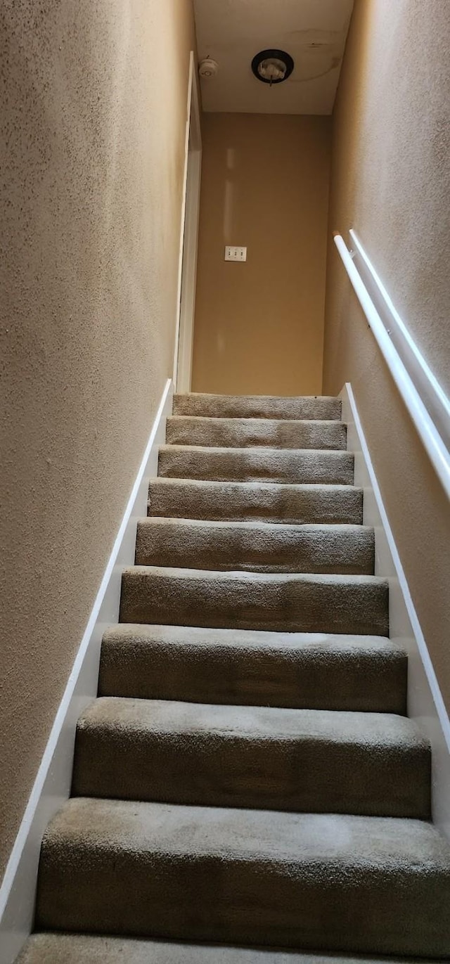 staircase featuring a textured wall