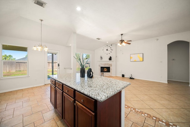 kitchen featuring arched walkways, vaulted ceiling, baseboards, and a premium fireplace