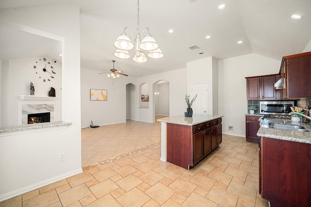 kitchen with visible vents, arched walkways, lofted ceiling, a premium fireplace, and stainless steel microwave