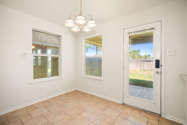 doorway featuring stone finish floor, an inviting chandelier, and baseboards