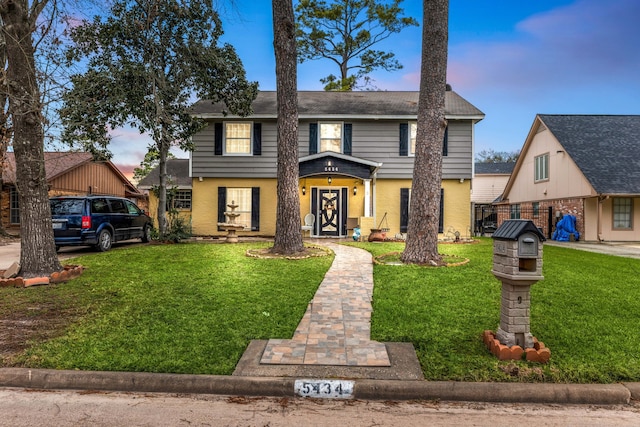 view of front of house with a front yard, brick siding, and fence