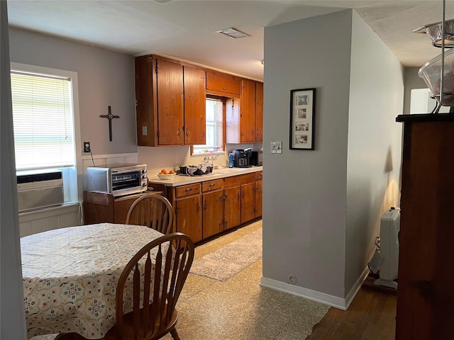 kitchen featuring a toaster, baseboards, visible vents, brown cabinets, and light countertops