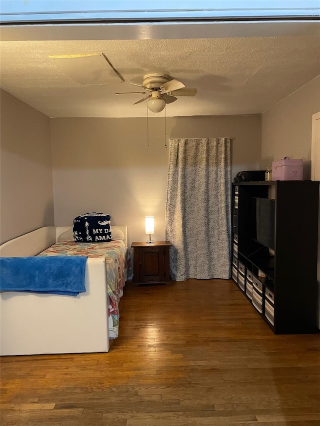 bedroom with a textured ceiling, ceiling fan, and wood finished floors