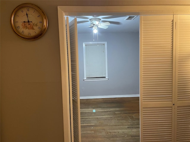 corridor featuring visible vents, baseboards, and wood finished floors