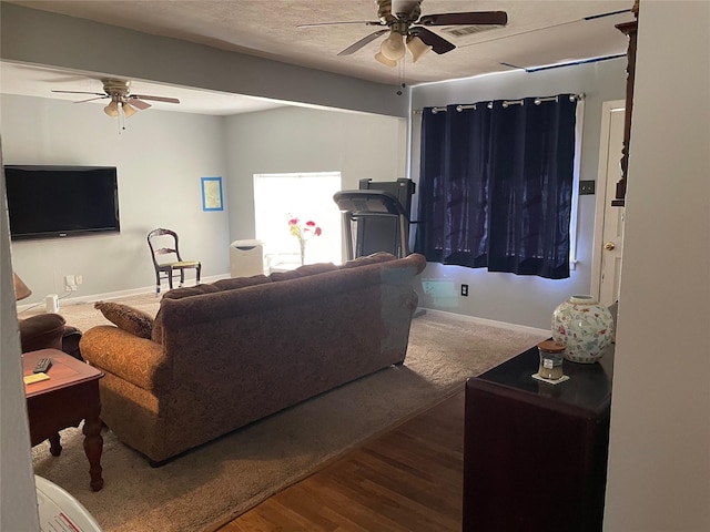 living room with ceiling fan, a textured ceiling, baseboards, and wood finished floors