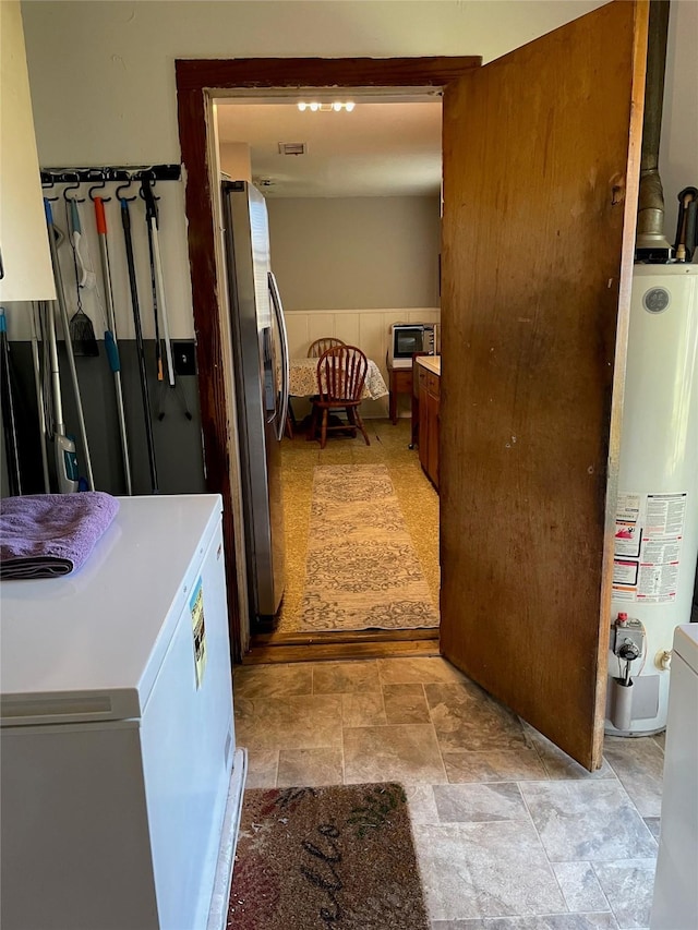 hall featuring stone finish flooring, gas water heater, and washer / dryer