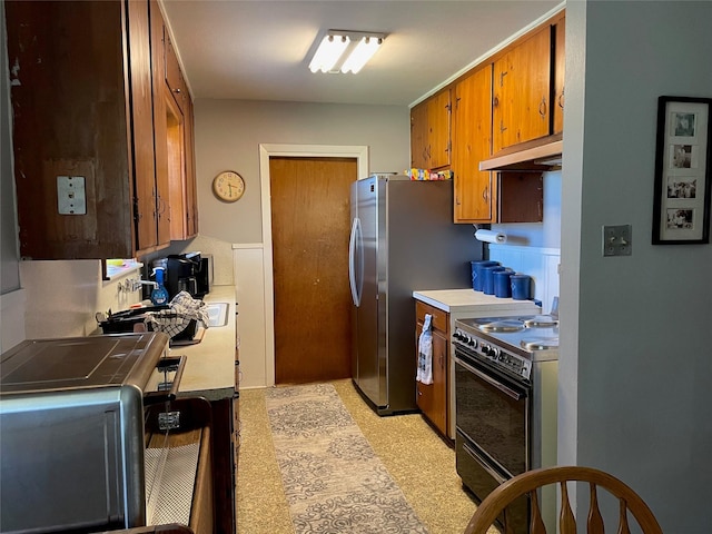 kitchen featuring brown cabinets, freestanding refrigerator, light countertops, black electric range, and under cabinet range hood