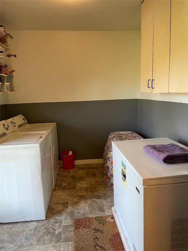 laundry area with stone finish floor, cabinet space, washer and clothes dryer, and baseboards