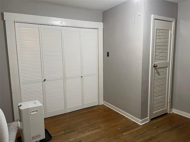 unfurnished bedroom featuring a closet, dark wood finished floors, and baseboards