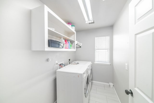 washroom with light tile patterned floors, laundry area, independent washer and dryer, and baseboards