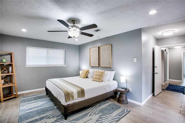 bedroom featuring baseboards, ceiling fan, visible vents, and light wood-style floors