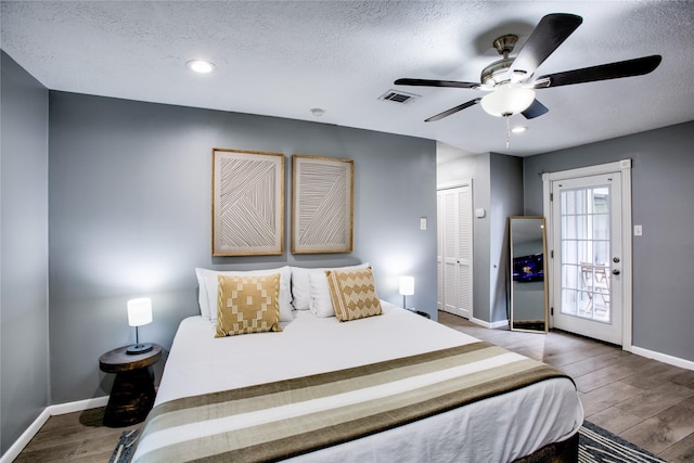 bedroom featuring a textured ceiling, a closet, wood finished floors, and baseboards