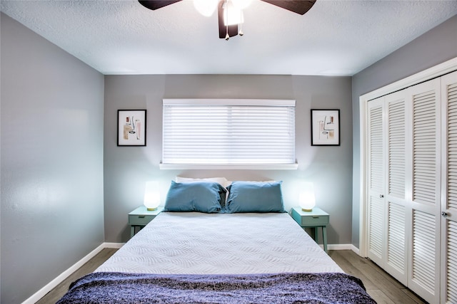 bedroom with light wood-style floors, a closet, a textured ceiling, and baseboards