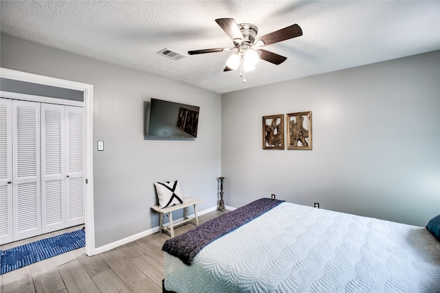 bedroom featuring visible vents, baseboards, ceiling fan, a textured ceiling, and light wood-style floors