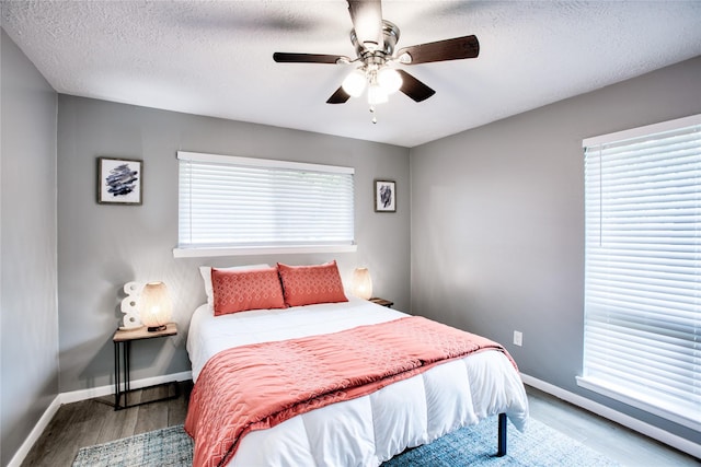 bedroom featuring a textured ceiling, wood finished floors, a ceiling fan, and baseboards