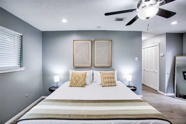 bedroom with a closet, baseboards, visible vents, and light wood finished floors