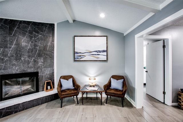 sitting room with light wood-type flooring, lofted ceiling with beams, baseboards, and a premium fireplace