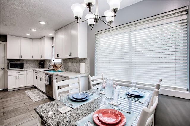 kitchen featuring pendant lighting, tasteful backsplash, light wood-style floors, white cabinets, and dishwasher