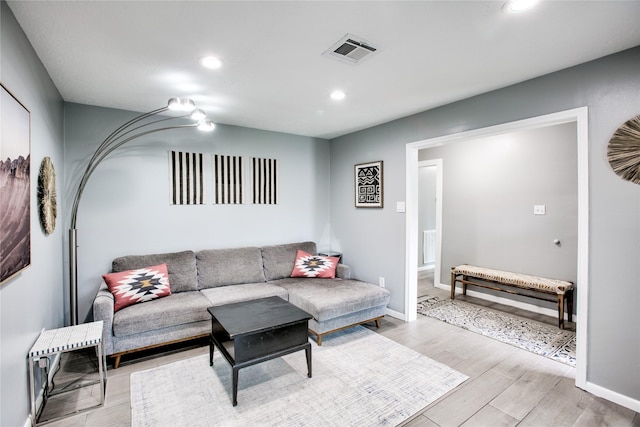 living room featuring light wood-type flooring, baseboards, visible vents, and recessed lighting