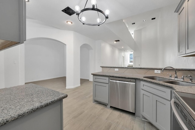 kitchen with dishwasher, gray cabinets, a sink, and light stone countertops