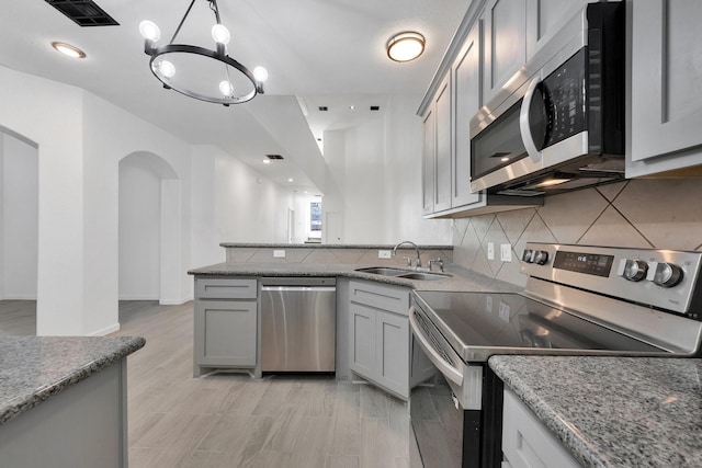 kitchen featuring pendant lighting, gray cabinets, visible vents, appliances with stainless steel finishes, and a sink