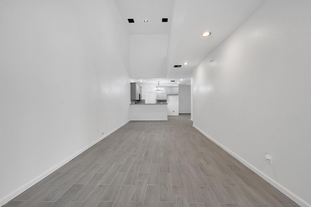 unfurnished living room featuring recessed lighting, baseboards, and light wood finished floors