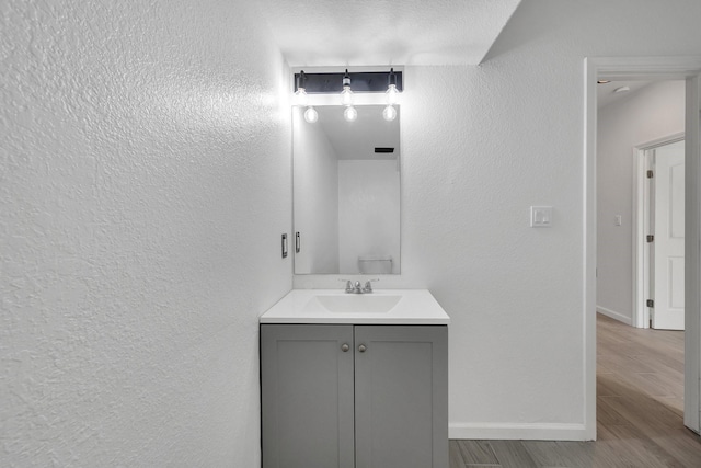 bathroom with wood tiled floor, a textured wall, vanity, and baseboards