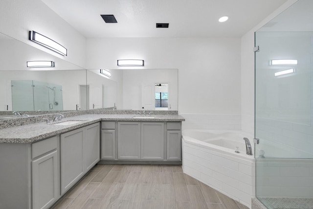 bathroom featuring a stall shower, a garden tub, a sink, and double vanity