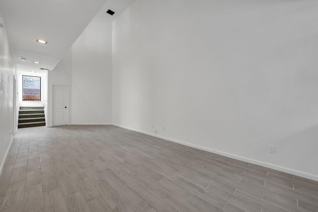 unfurnished room featuring light wood-style floors, stairs, baseboards, and recessed lighting