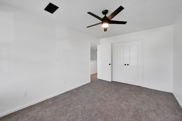 unfurnished bedroom with a closet, dark carpet, baseboards, and ceiling fan