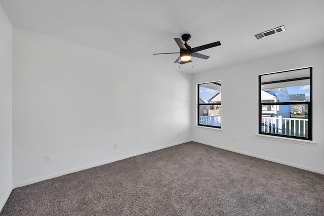 spare room featuring a ceiling fan, visible vents, dark carpet, and baseboards