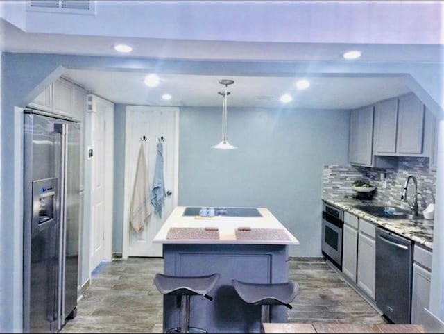 kitchen featuring pendant lighting, black appliances, a sink, and gray cabinetry