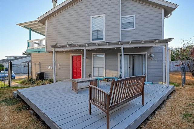 back of property with a balcony, fence, and a wooden deck