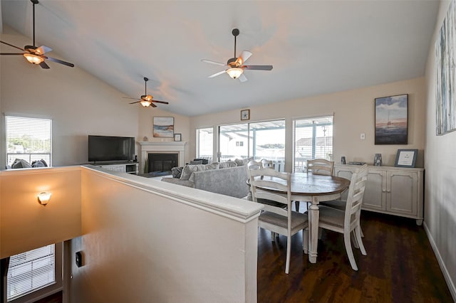 dining space featuring dark wood-style floors, a glass covered fireplace, and vaulted ceiling