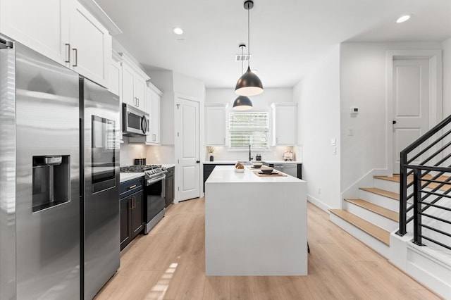 kitchen featuring white cabinets, appliances with stainless steel finishes, light countertops, and pendant lighting