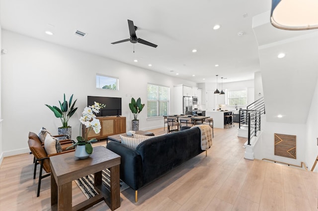 living room with a healthy amount of sunlight, light wood-style flooring, stairs, and recessed lighting