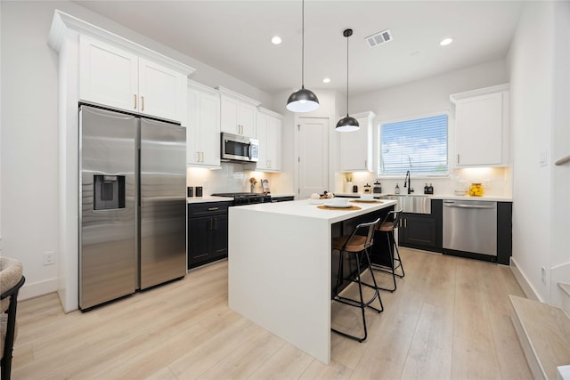 1909 Johanna Dr, Houston, TX 77055 - kitchen featuring stainless steel appliances, a sink, light wood-style floors, light countertops, and white cabinets