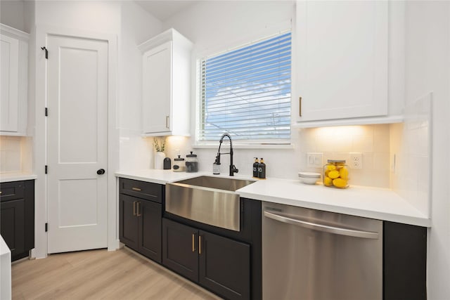 1909 Johanna Dr, Houston, TX 77055 - kitchen with stainless steel dishwasher, a sink, white cabinetry, decorative backsplash, and light wood-style floors
