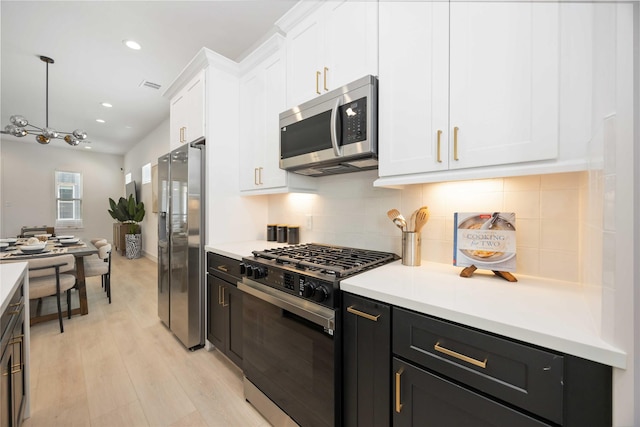 1909 Johanna Dr, Houston, TX 77055 - kitchen with stainless steel appliances, white cabinets, tasteful backsplash, light wood-type flooring, and light countertops