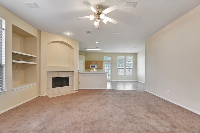 unfurnished living room featuring baseboards, built in features, a ceiling fan, carpet, and a fireplace